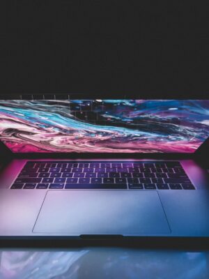 High angle of half opened modern laptop with colorful abstract picture on desktop placed on table in dark room